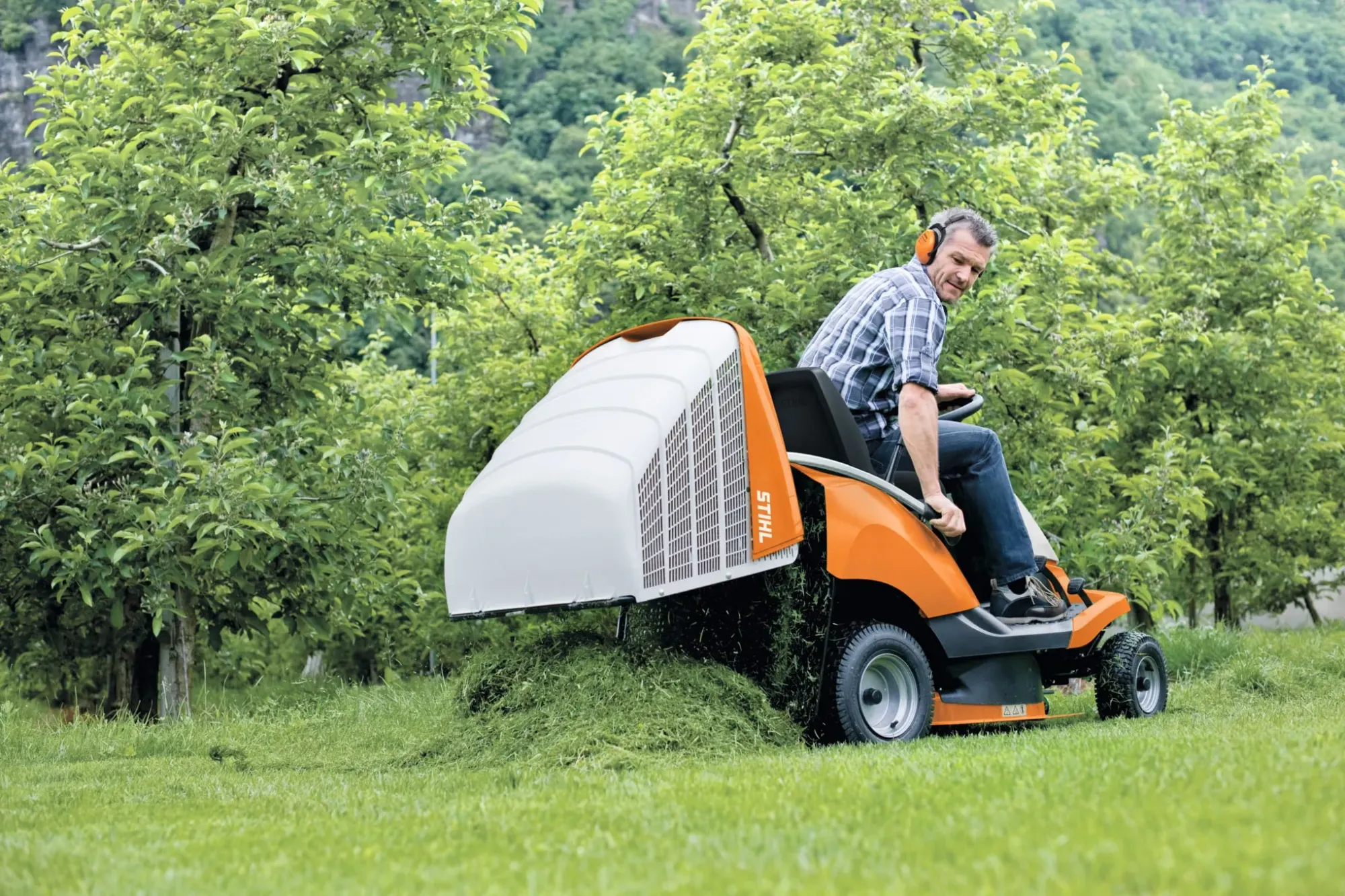 A STIHL technician servicing a ride-on mower in a workshop